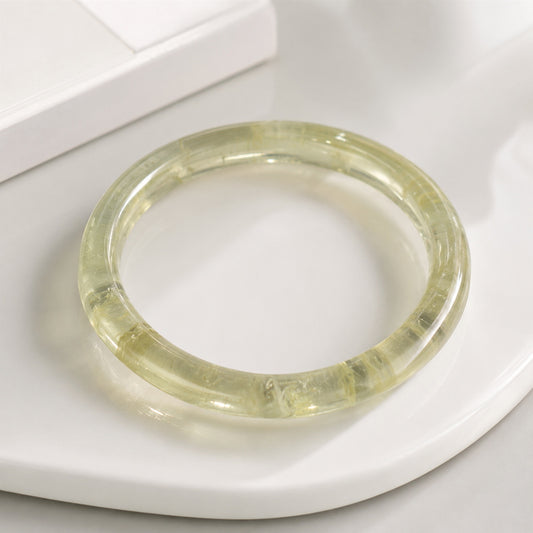 Close-up of a polished yellow citrine bangle on a white tray