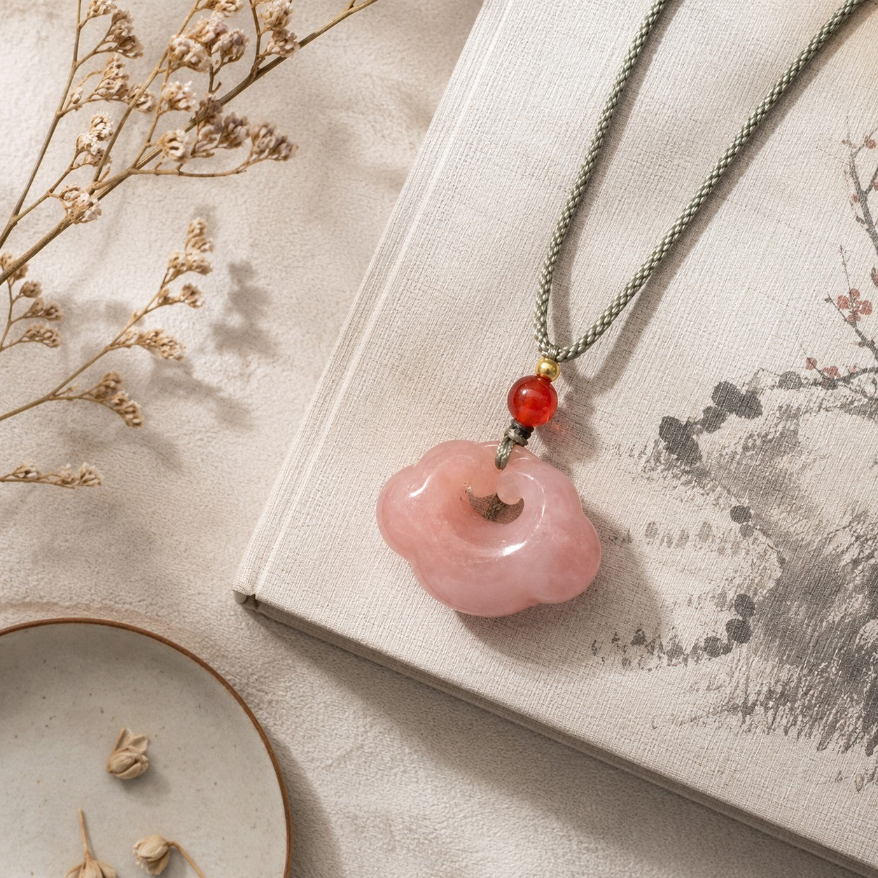 Quartzite jade cloud pendant necklace displayed on a traditional style book