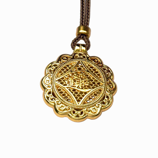 The reversible back side of a sand gold charm, showcasing deeply engraved Chinese characters for bringing in wealth and treasures on a delicate filigree mesh background.