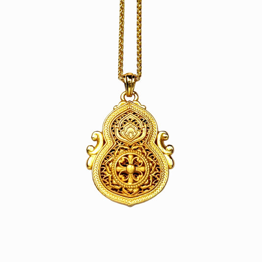 The reversible back side of a sand gold gourd necklace, showcasing a smooth all-gold brushed finish with a deeply engraved cross-vajra motif on a delicate openwork lattice background.