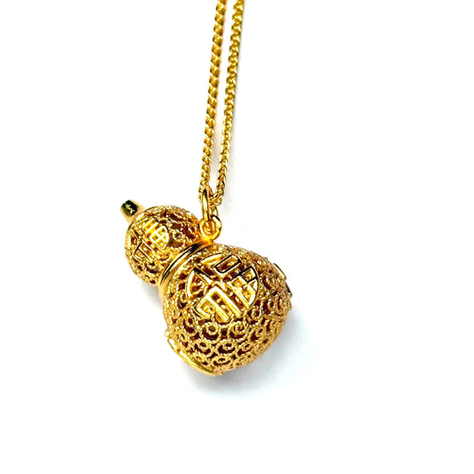 An angled studio view of a luxurious sand gold kinetic Hulu amulet with shadow detailing, highlighting the dimensional wire lattice and enamel artwork.
