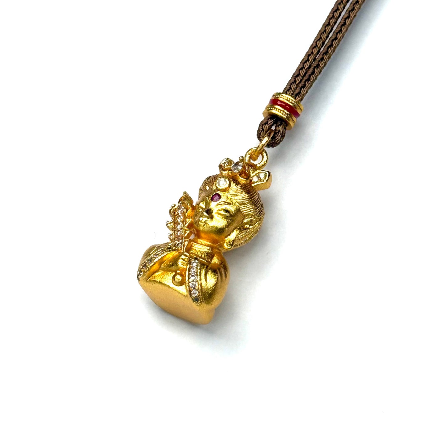 A regal sand gold sacred deity meditation amulet necklace with bright red and blue gemstones, displayed elegantly against a rustic driftwood branch.
