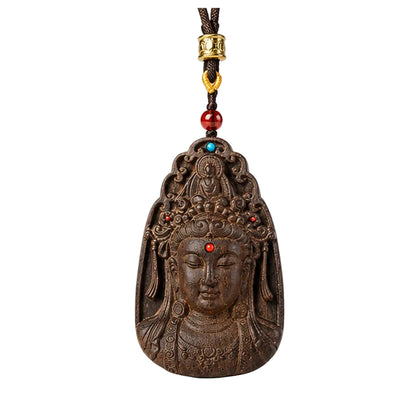 Front view of an agarwood Guanyin pendant with dark braided cord and red accent bead