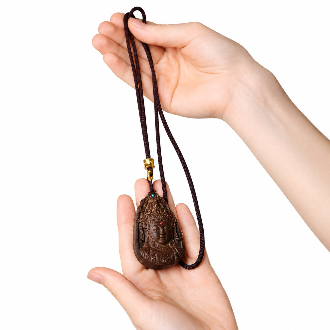 Agarwood Guanyin pendant held in hands, showing the necklace cord and scale