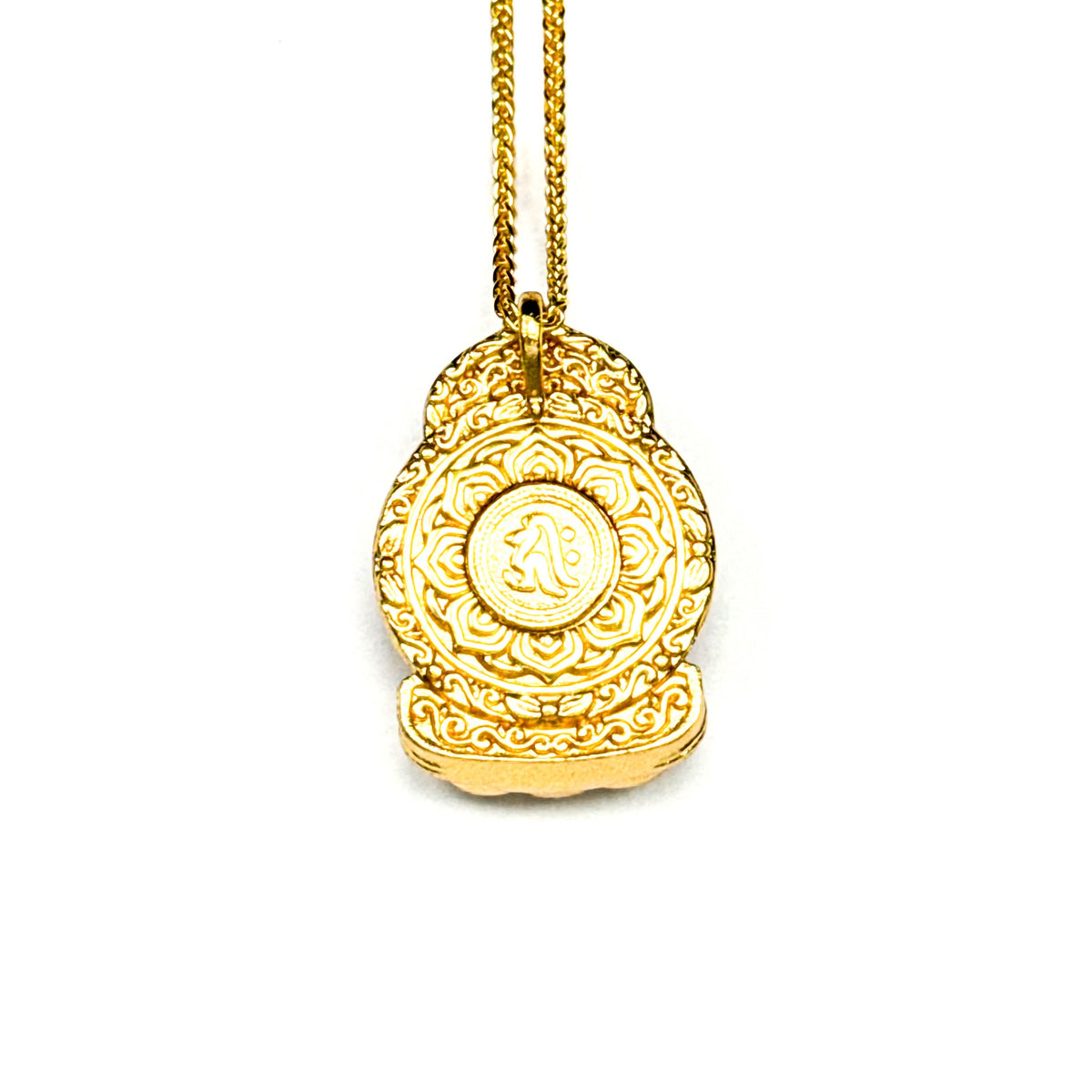 The intricately carved back side of a gold Buddha pendant, revealing a stunning lotus mandala design with a central Sanskrit seed syllable on a white background.
