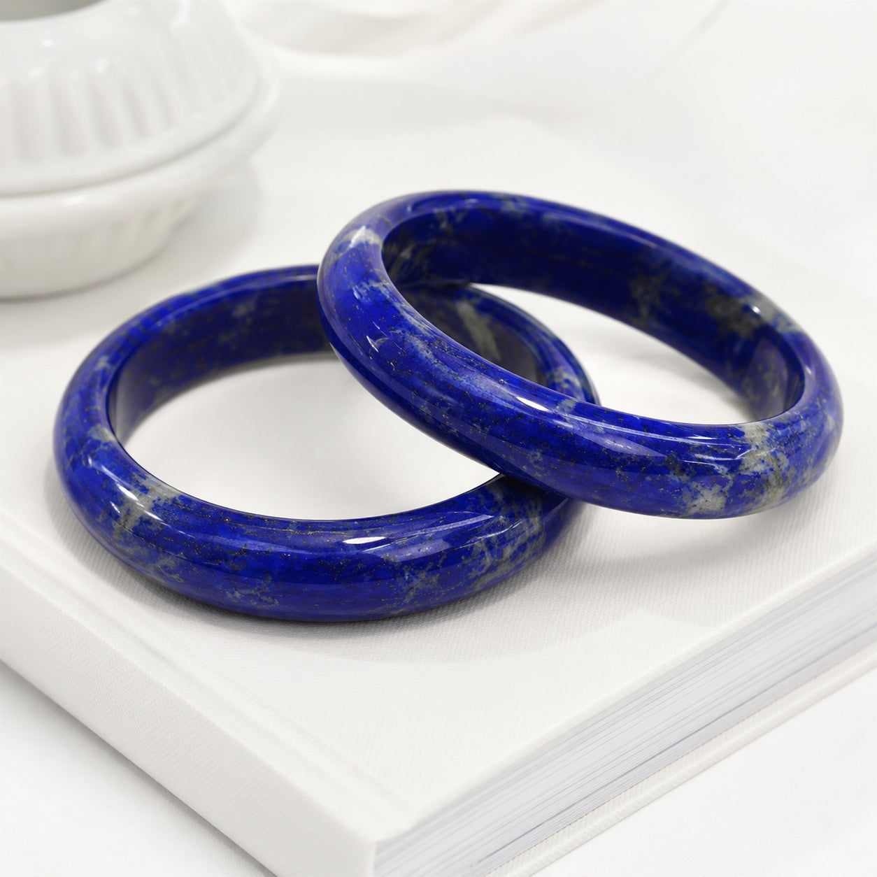 Two deep blue lapis lazuli bangles displayed on a white book