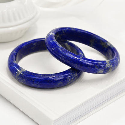 Two deep blue lapis lazuli bangles displayed on a white book