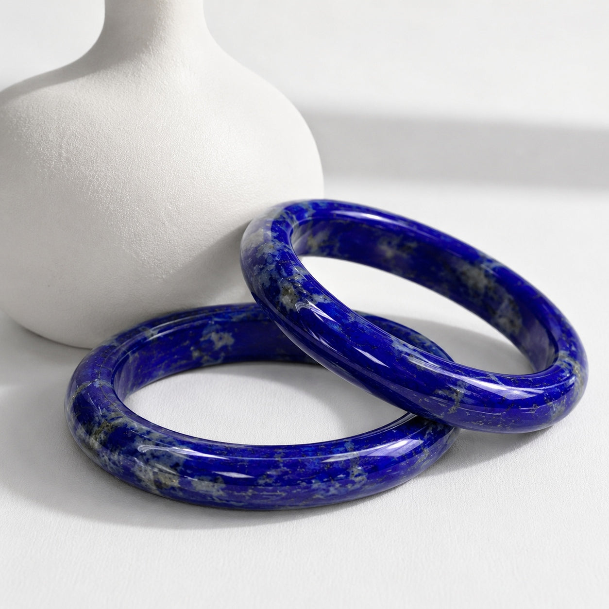 Pair of polished lapis lazuli bangles with deep blue stone patterns