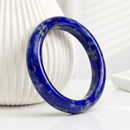Polished blue lapis lazuli bangle standing beside a white vase