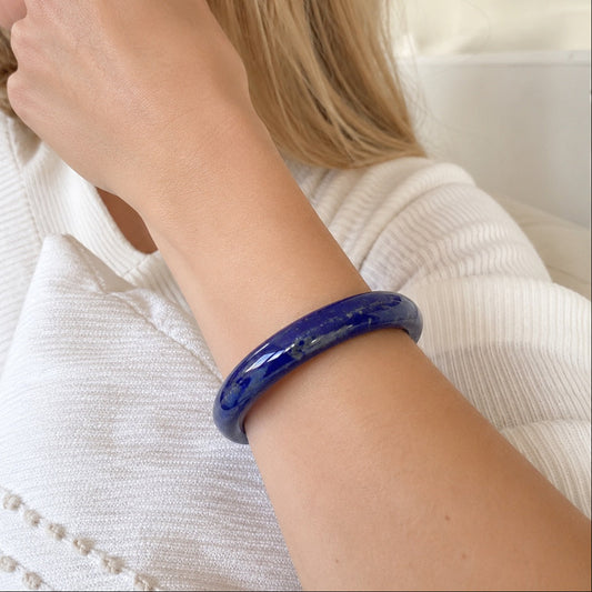 Blue lapis lazuli bangle worn on wrist with a white sweater