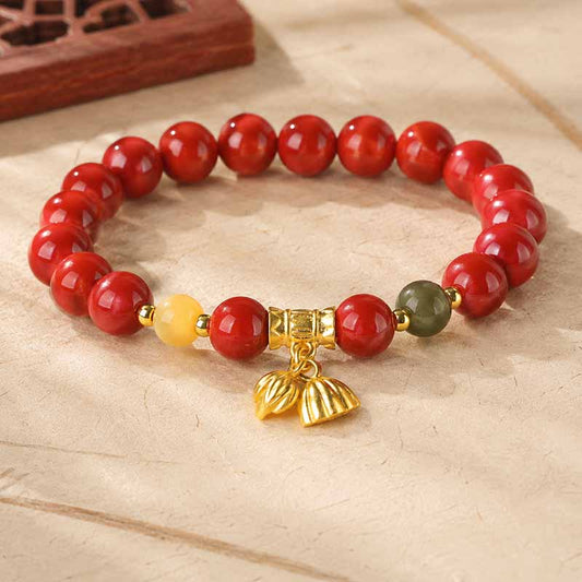 Red cinnabar beaded bracelet with gold-tone charm and accent beads