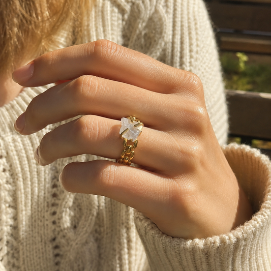 Woman wearing a gold-plated chain-link statement ring with an irregular clear stone