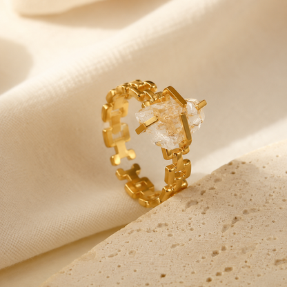 Close-up of a gold-tone stainless steel open ring with an irregular clear stone