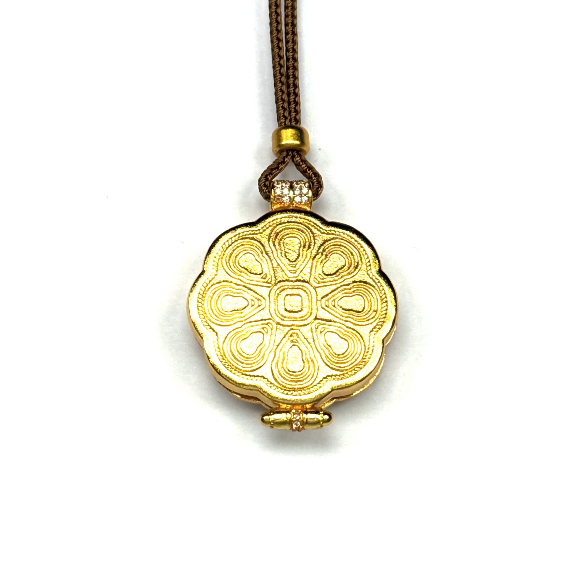 The back view of a golden Buddhist locket pendant, showcasing intricately embossed lotus and mandala floral patterns.