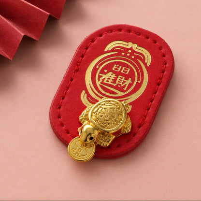 Close-up of gold-tone Money-Biting Turtle charm on a stitched red backing