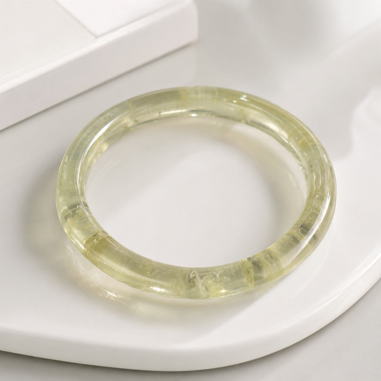 Close-up of a polished yellow citrine bangle on a white tray