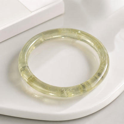 Close-up of a polished yellow citrine bangle on a white tray