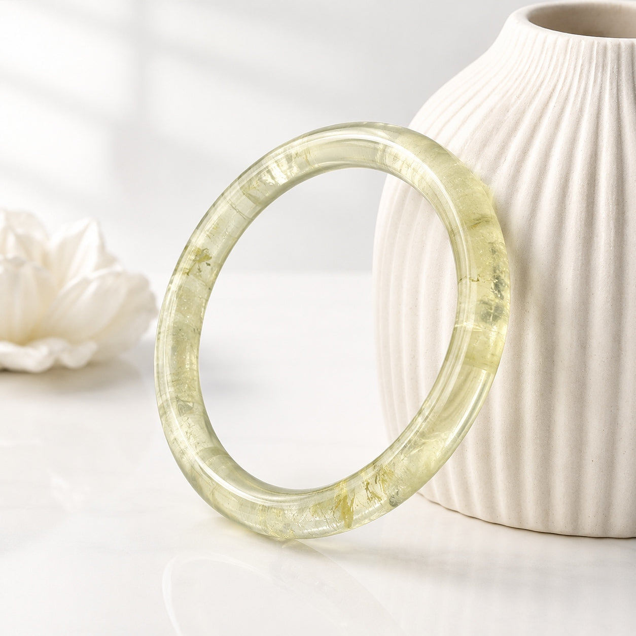 Polished citrine bangle standing beside a white ceramic vase