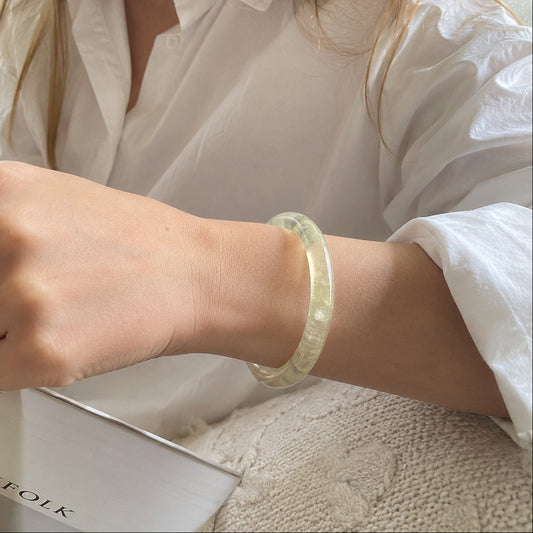Yellow citrine bangle worn on wrist with a white outfit