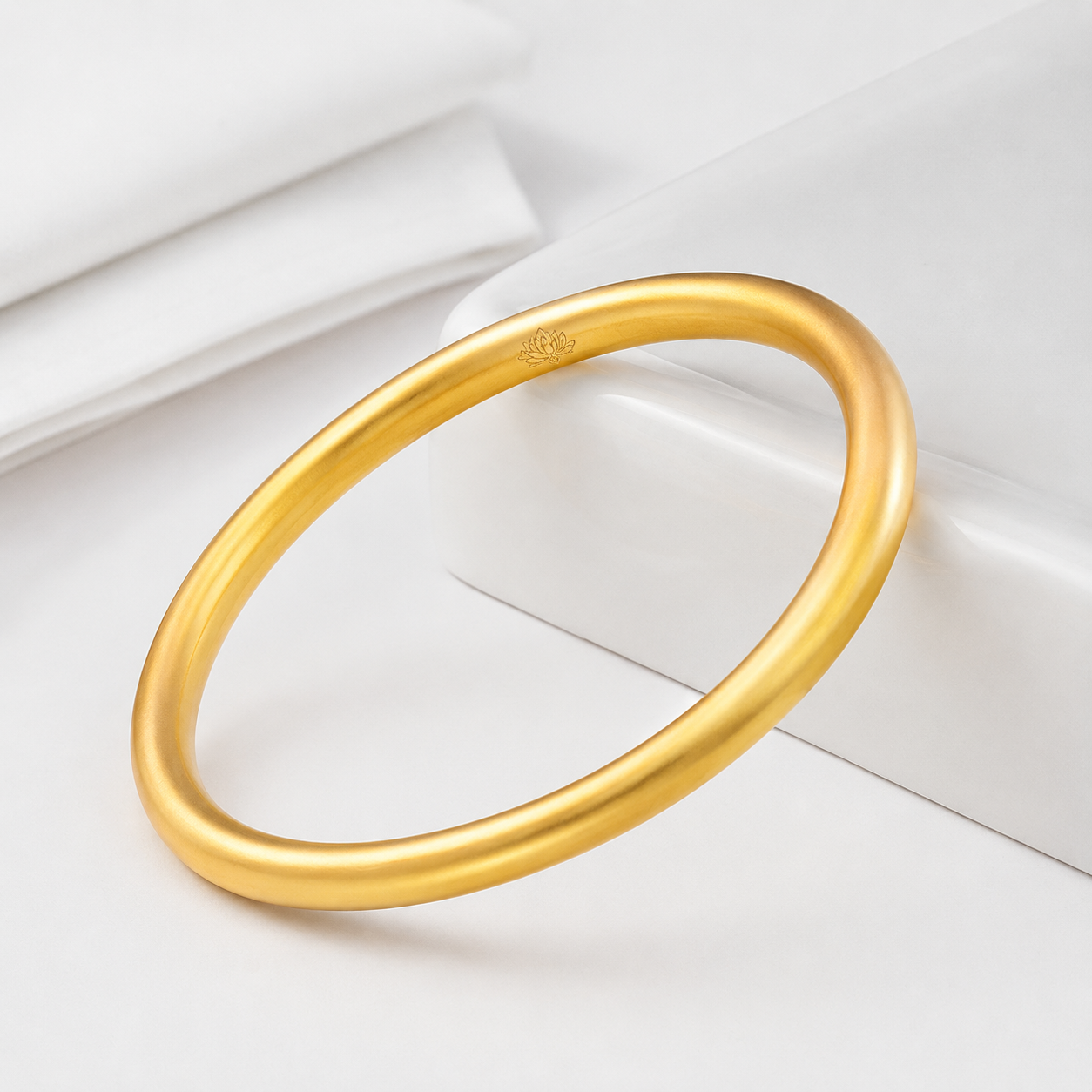 Minimalist gold-tone sandgold bangle with lotus detail