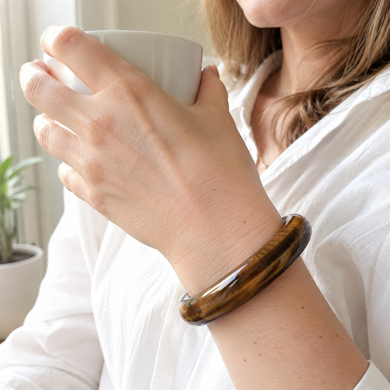 Woman wearing a tiger’s eye bangle bracelet indoors