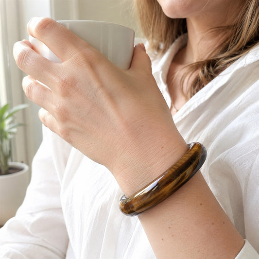 Woman wearing a tiger’s eye bangle bracelet indoors
