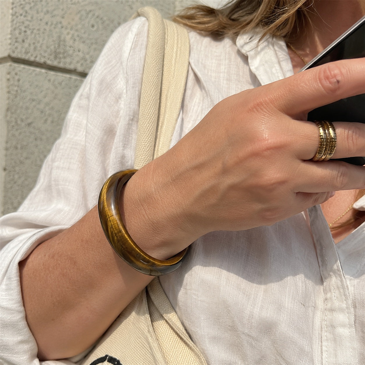 Woman wearing a golden tiger’s eye bangle bracelet with a casual outfit