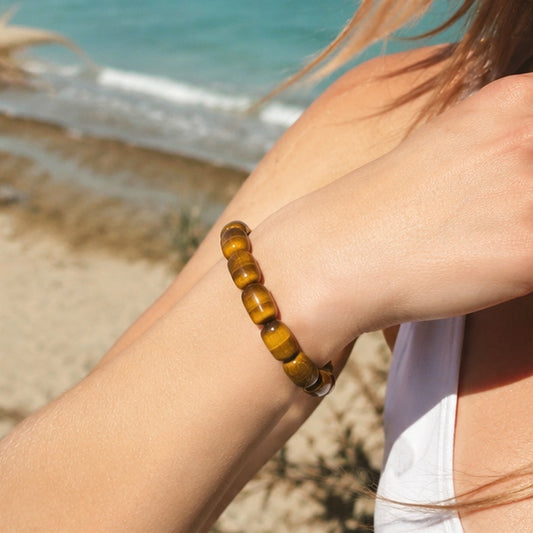 Woman wearing a golden tiger’s eye barrel bead bracelet by the beach