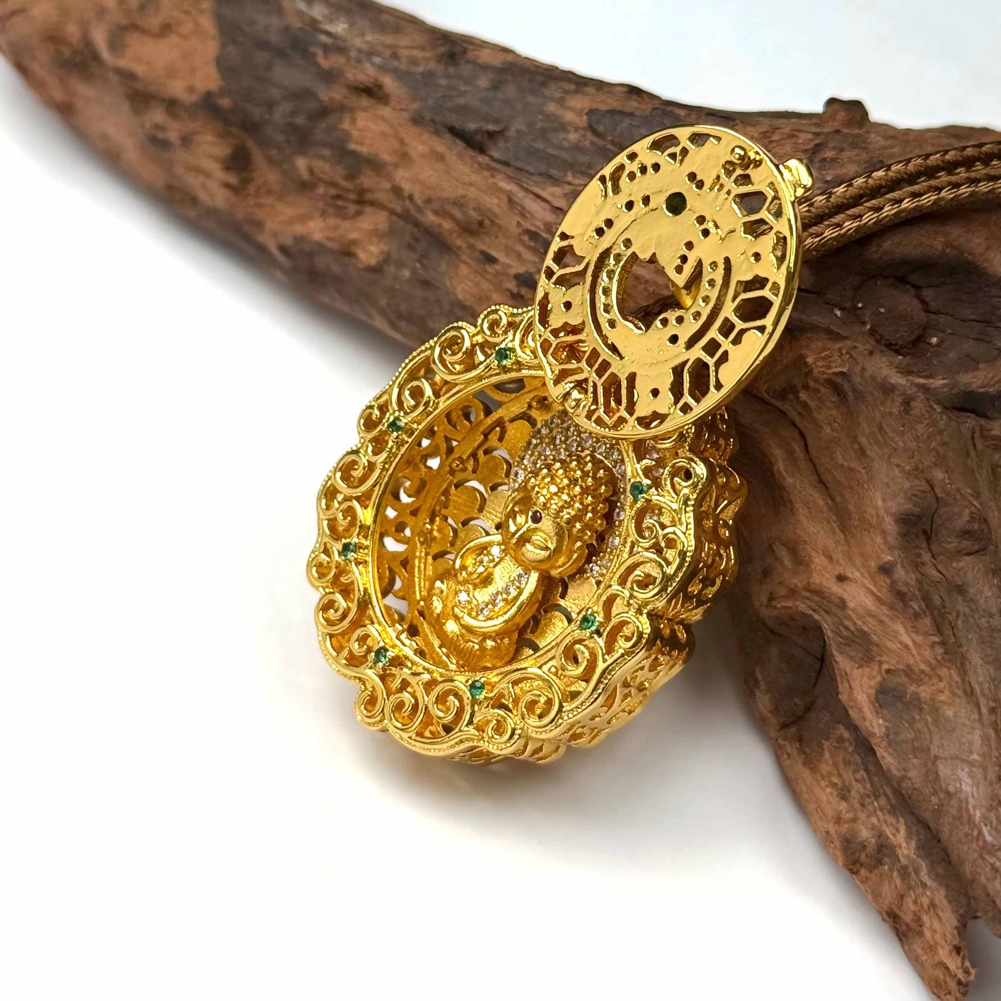 An opened sand gold locket showing a beautifully detailed baby Buddha shrine inside, displayed elegantly on natural driftwood.