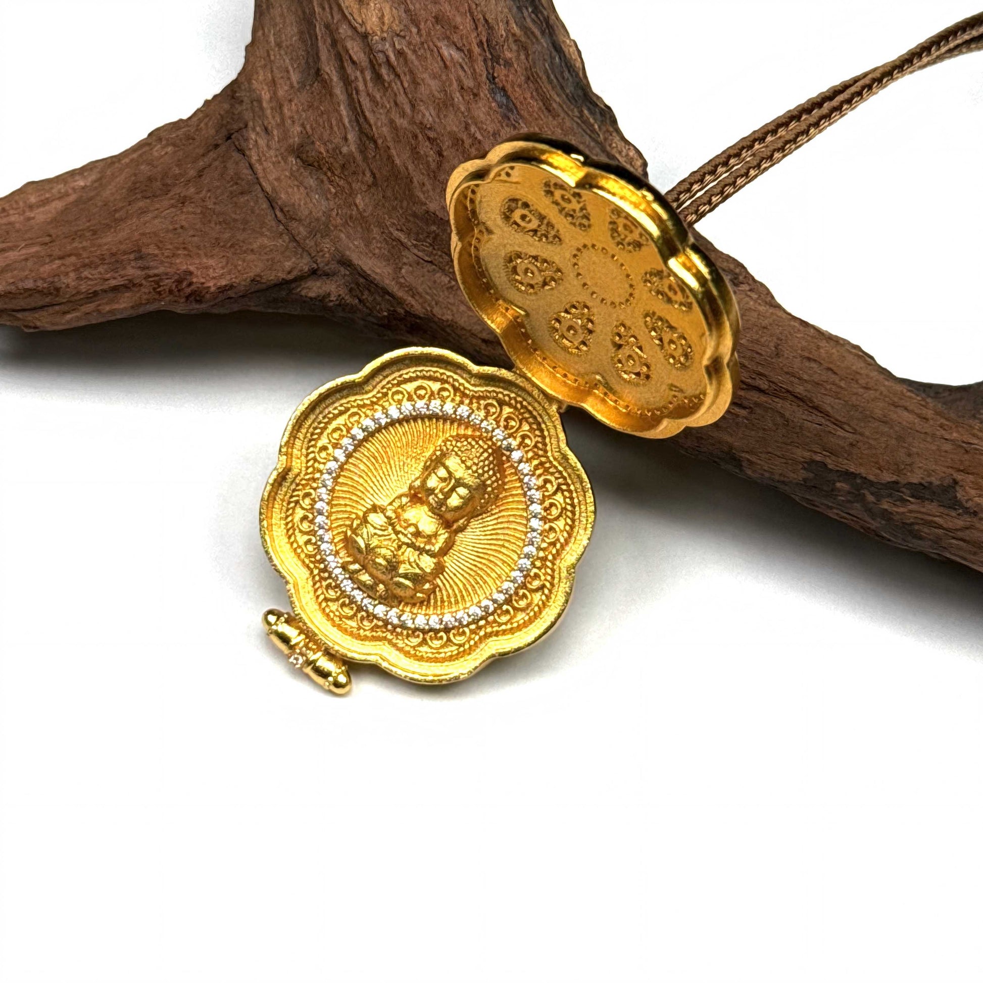 A vintage-style green enamel and gold lotus locket pendant resting elegantly on a piece of rustic driftwood.