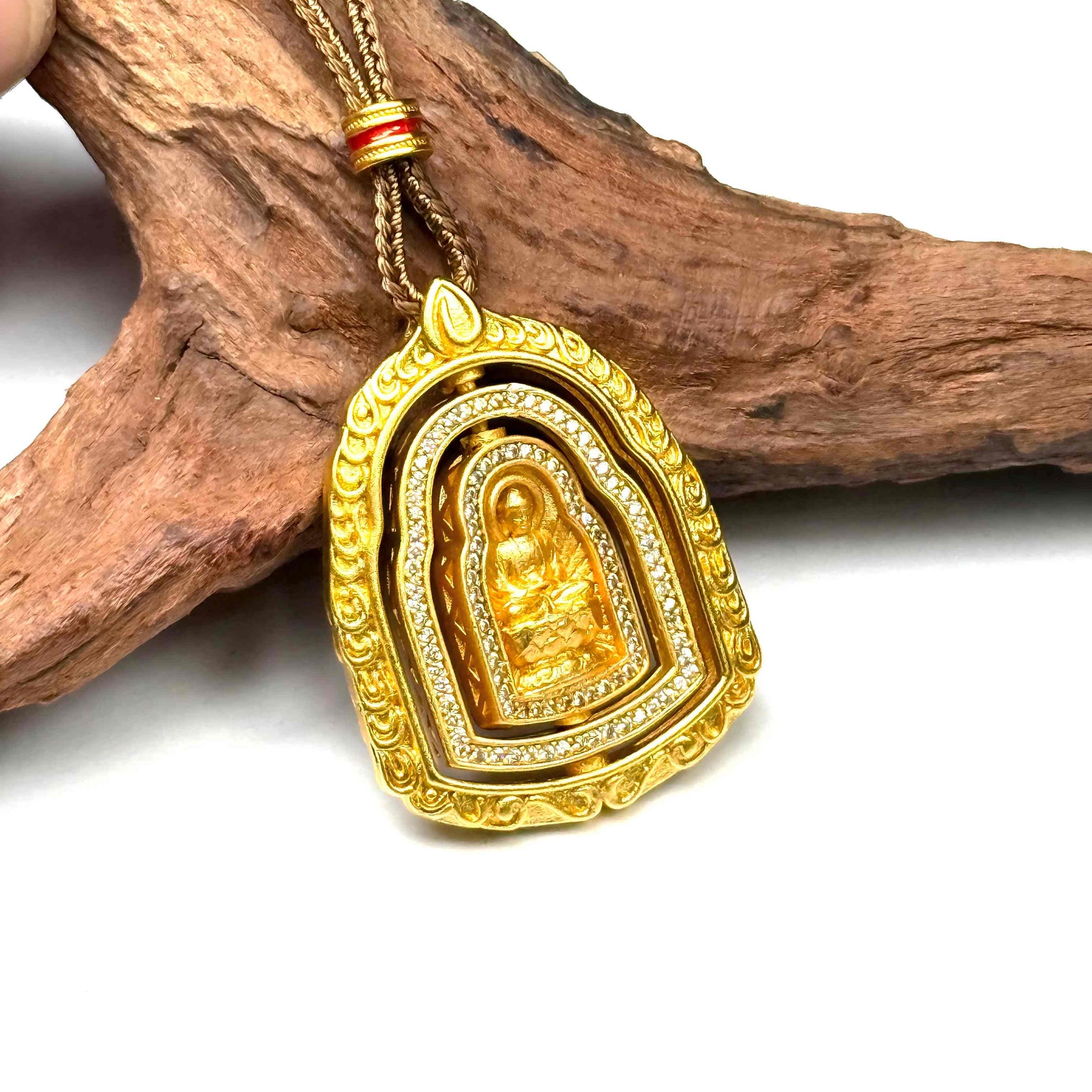 An interactive gold Buddha locket charm shown during rotation, revealing its intricately sculpted reverse side against a driftwood setting.