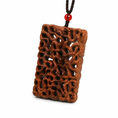 Angled view of a carved jujube wood dragon pendant with red accent bead