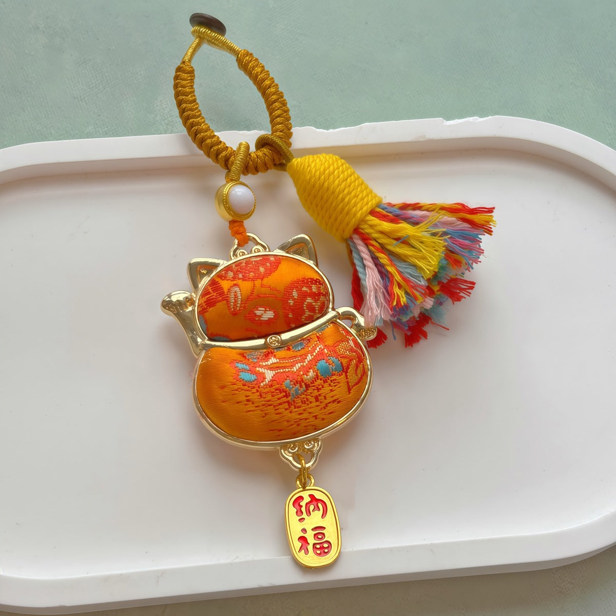 Lucky cat brocade tassel hanging charm in orange with gold-tone trim and multicolor tassel
