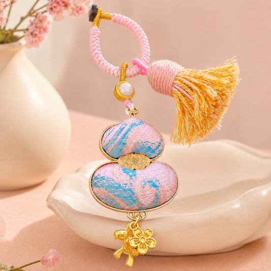 Pink brocade lucky gourd hanging charm with cotton tassel and gold-tone lucky charms