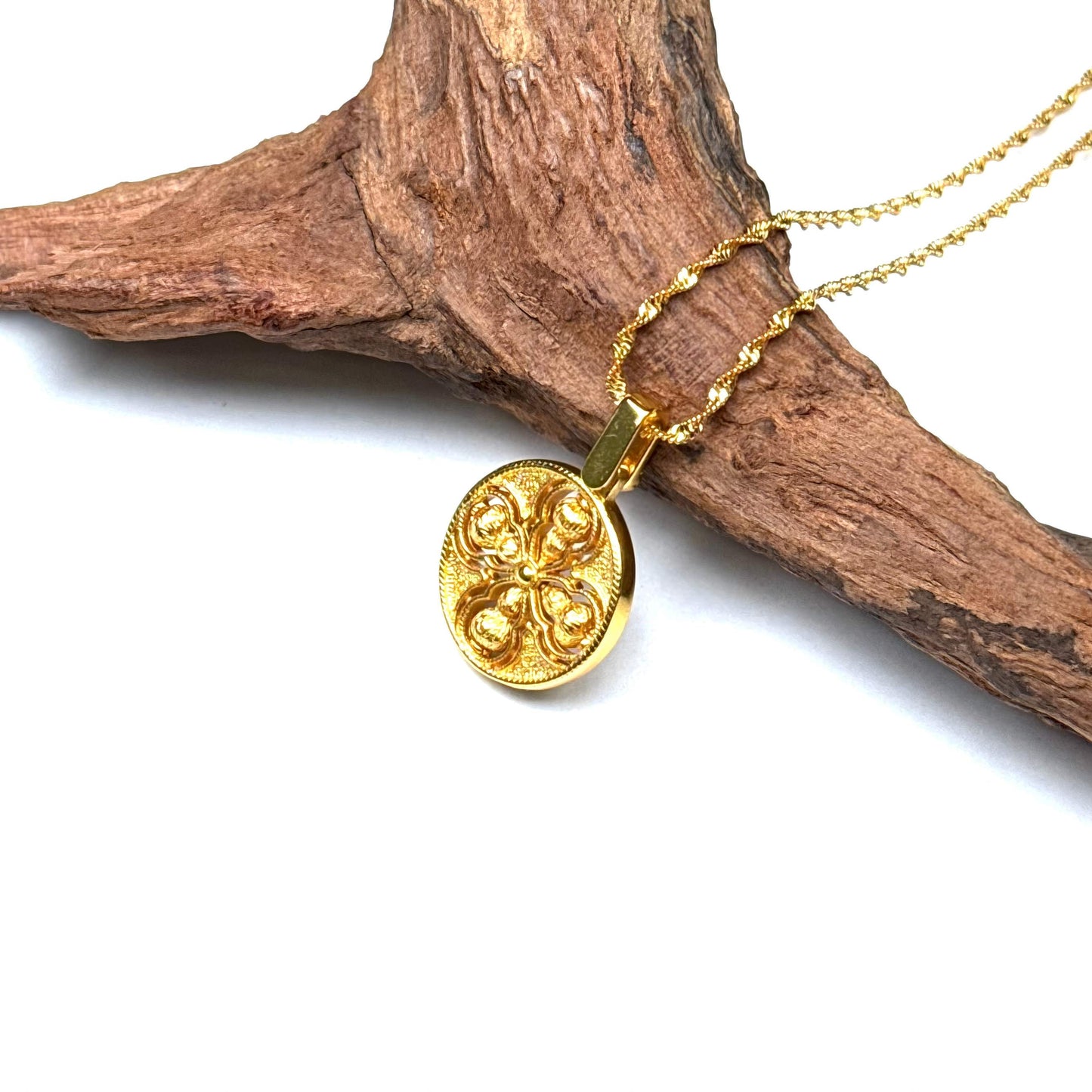 A traditional sand gold Vajra protection talisman resting on a piece of rustic driftwood, highlighting its warm golden luster and spiritual Zen aesthetic.