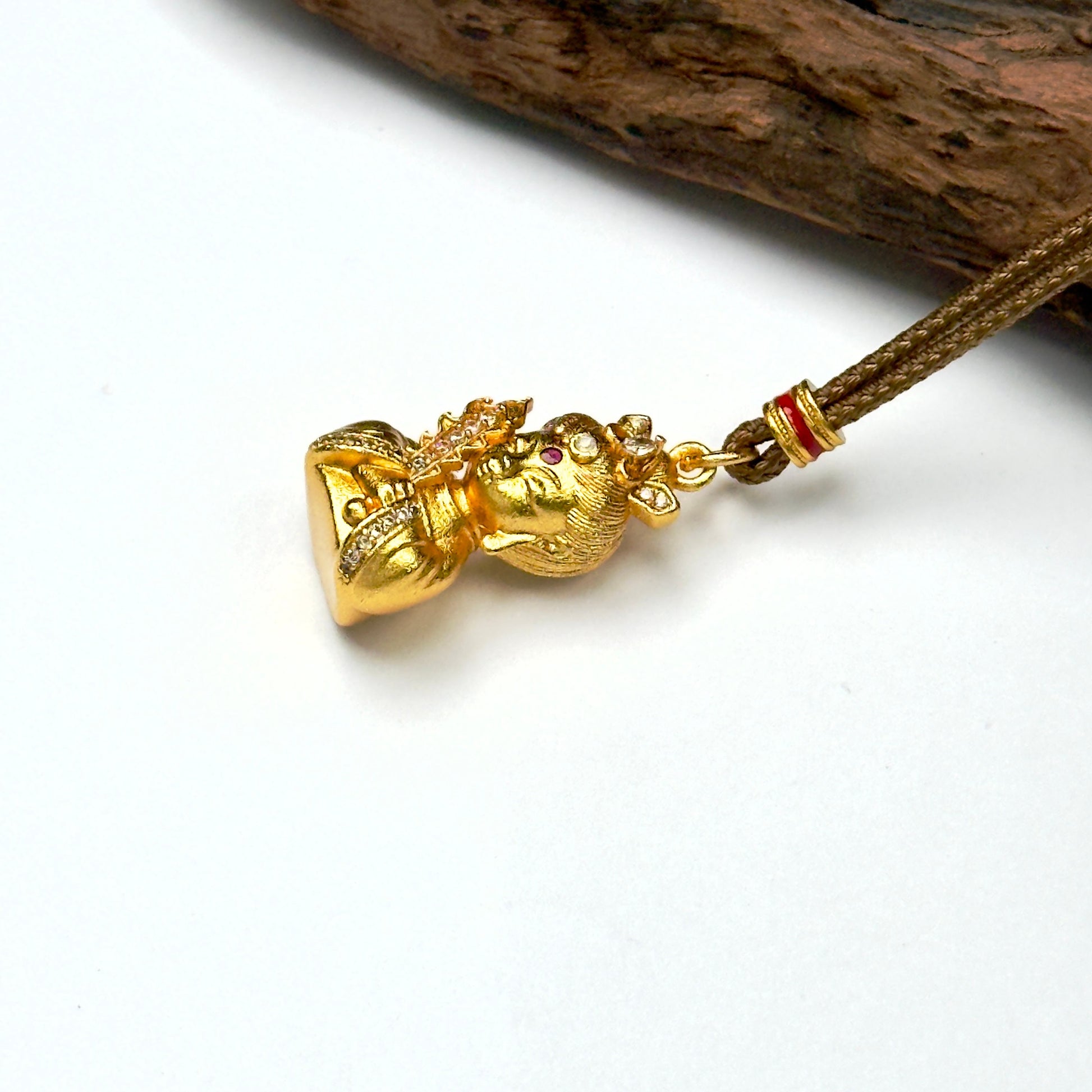 Macro close-up shot of an ancient style brushed sand gold Buddha deity charm resting against wood, capturing the precise rhinestone pavé rows.