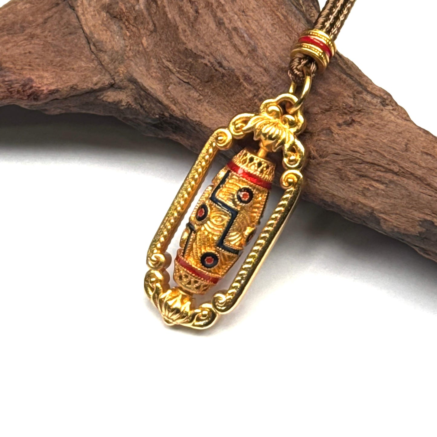 Macro detail of a luxurious gold and enamel spinning Dzi bead pendant on natural wood, highlighting the protective eye patterns and fidget-friendly design.