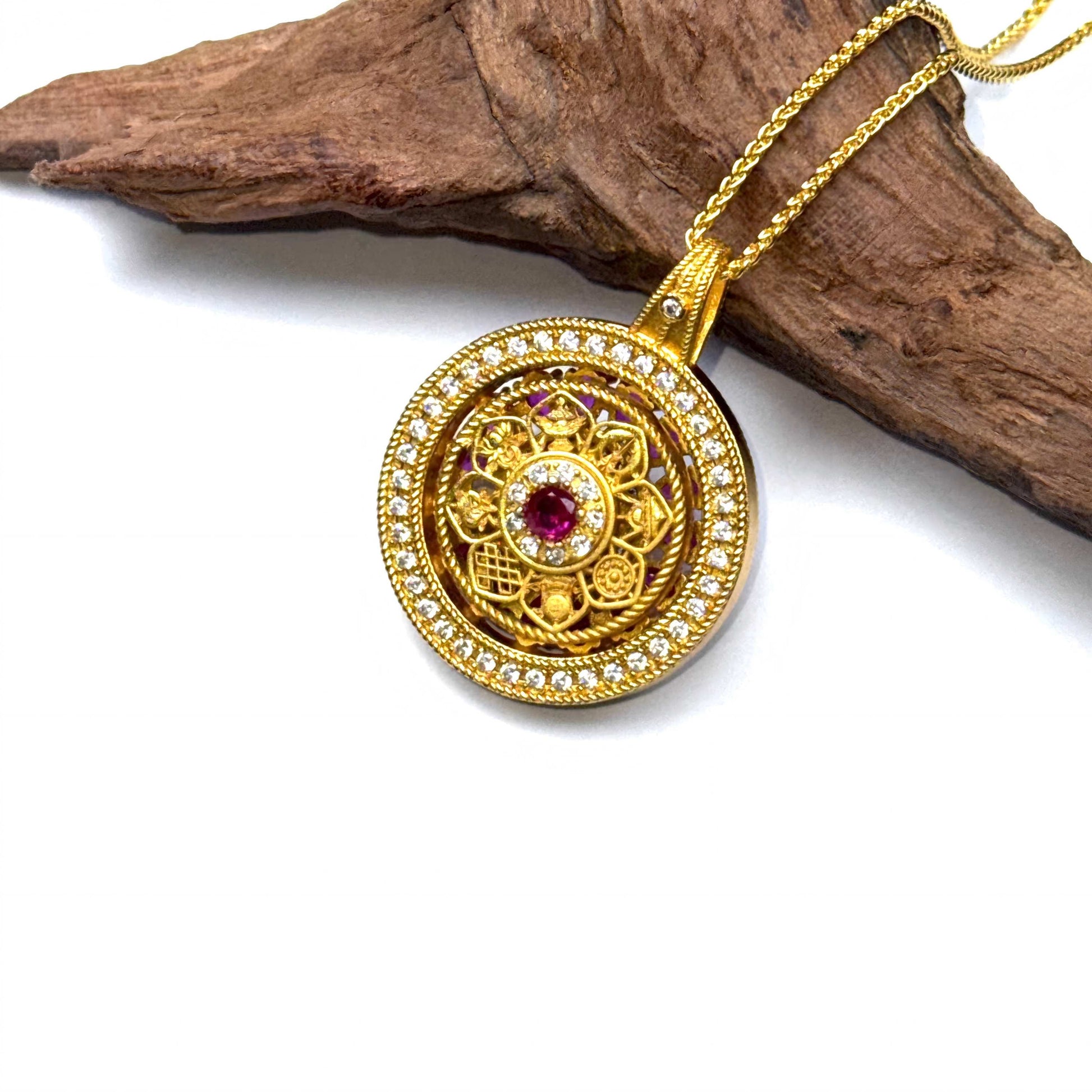The embossed filigree back side of a golden spinning amulet displayed elegantly on a piece of natural rustic wood.