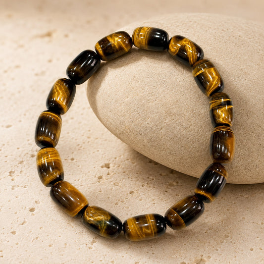 Natural tiger’s eye barrel bead bracelet displayed on stone prop