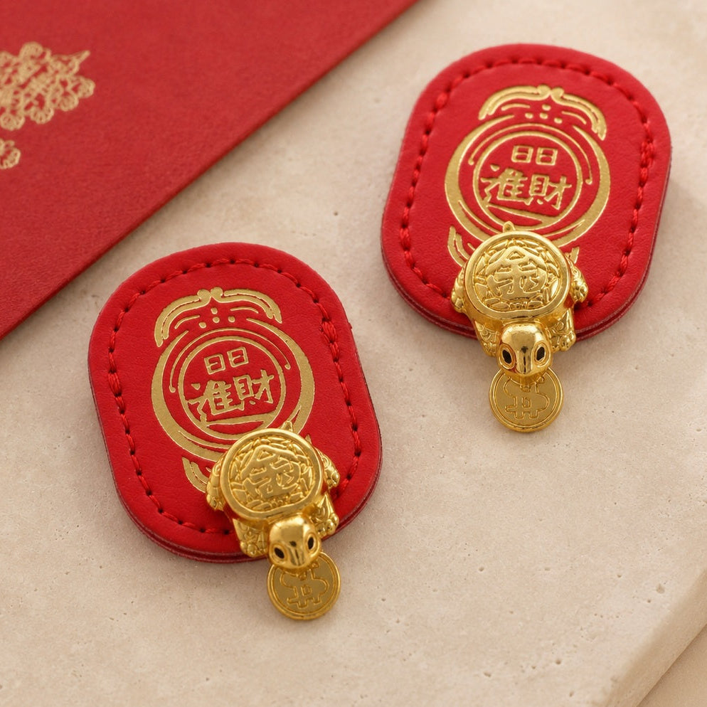 Two red-backed Money-Biting Turtle wealth charms displayed with a red envelope