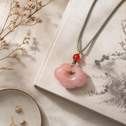 Quartzite jade cloud pendant necklace displayed on a traditional style book