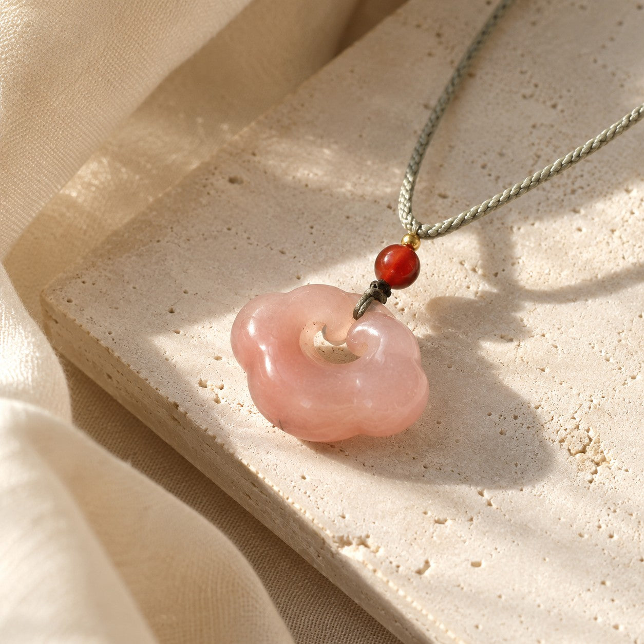 Pink quartzite jade auspicious cloud pendant with red bead and gray cord
