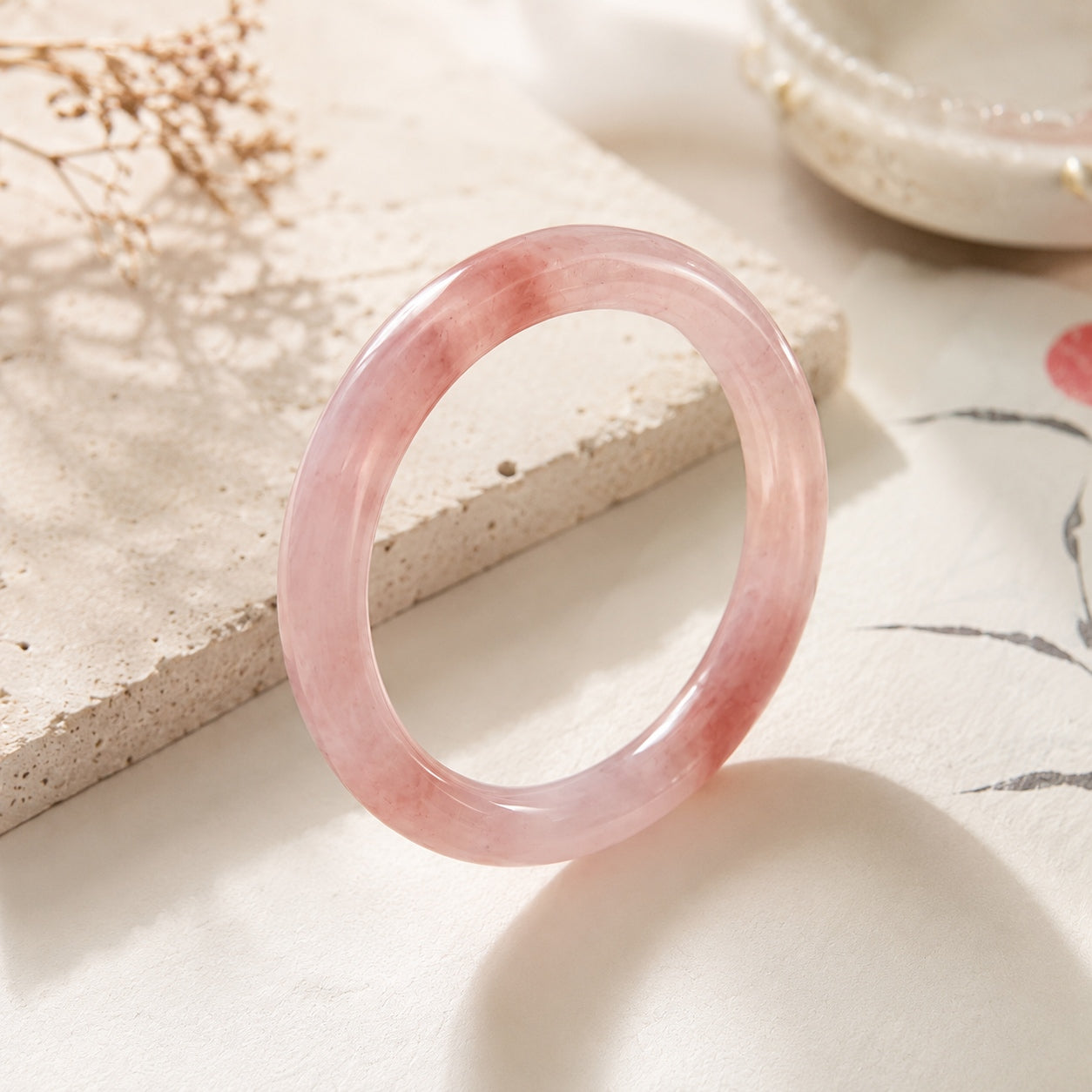 Soft pink quartzite jade bangle bracelet standing upright in an elegant product display