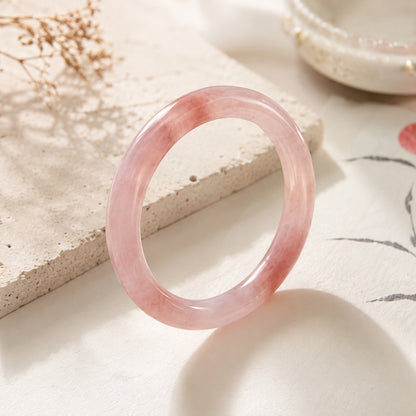 Soft pink quartzite jade bangle bracelet standing upright in an elegant product display