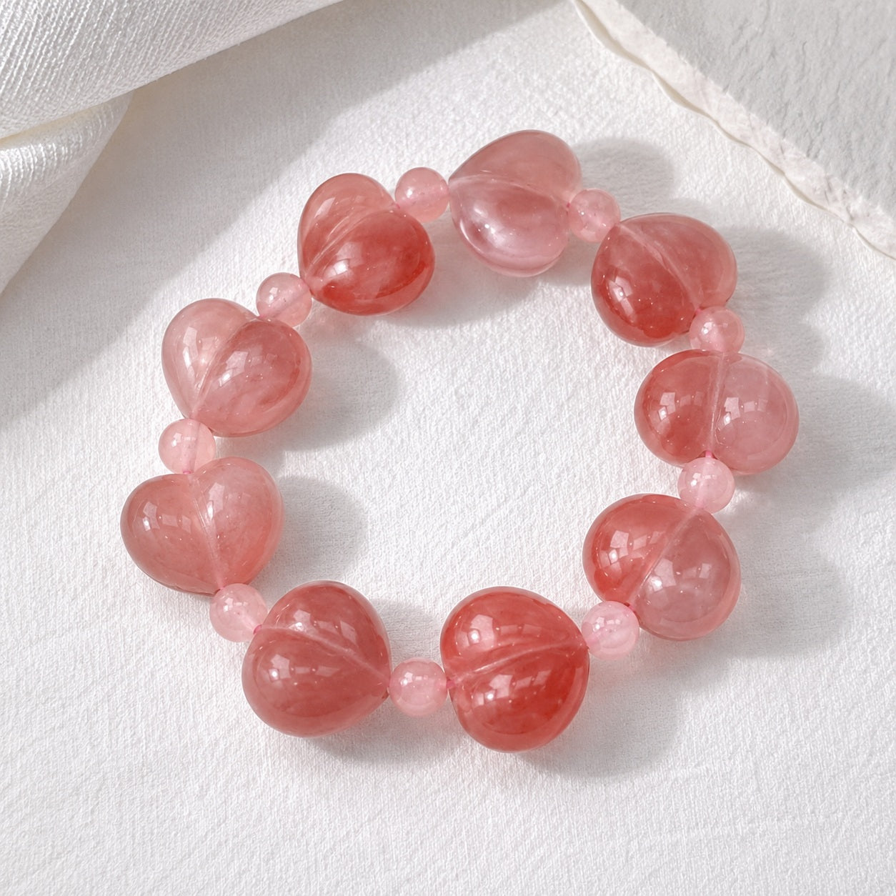 Pink quartzite jade heart bead bracelet on a white textured background