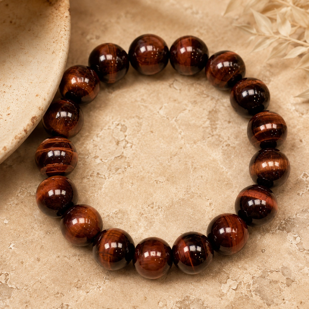 Red tiger’s eye beaded bracelet displayed on a stone surface