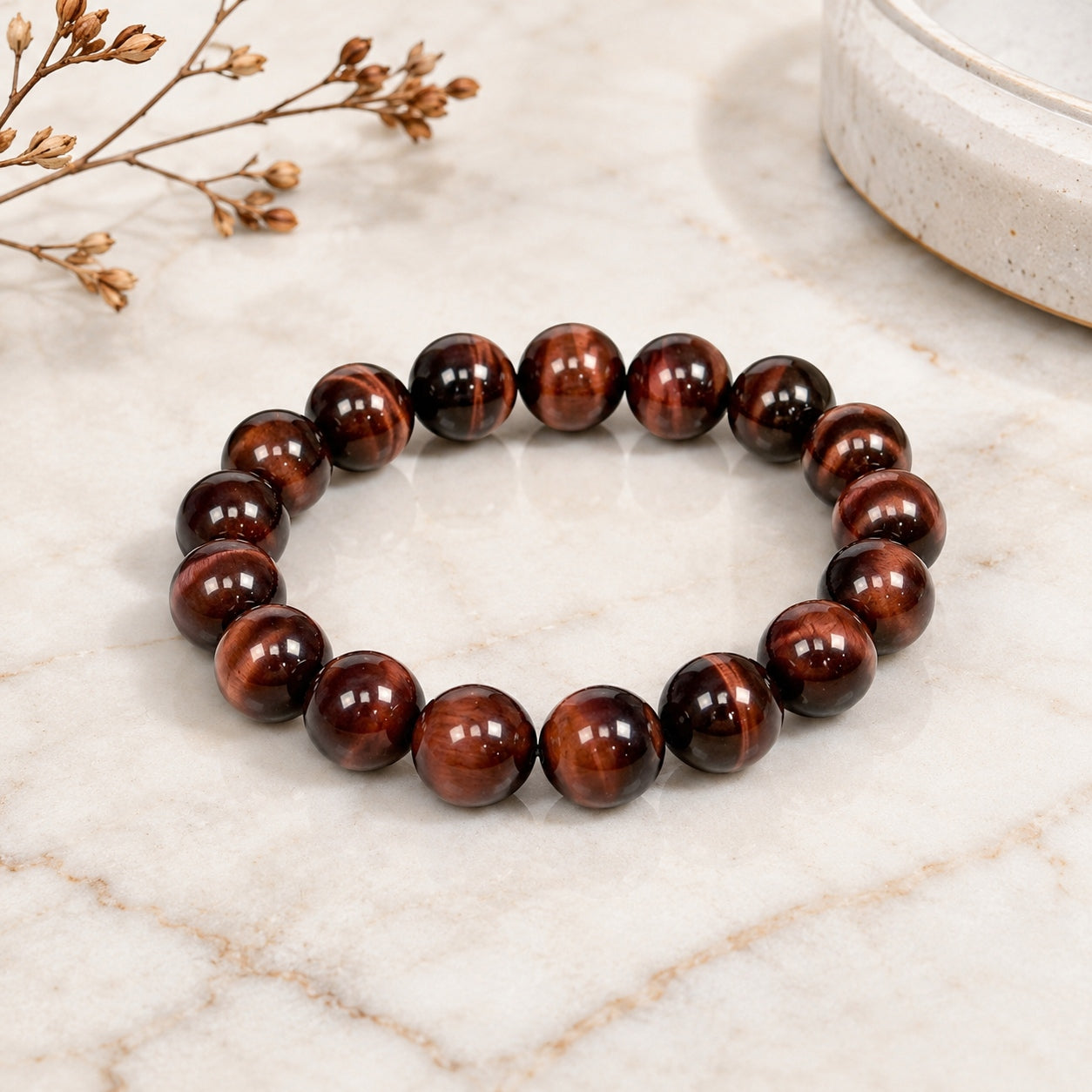 Polished red tiger’s eye bead bracelet on a light marble surface