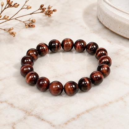 Polished red tiger’s eye bead bracelet on a light marble surface
