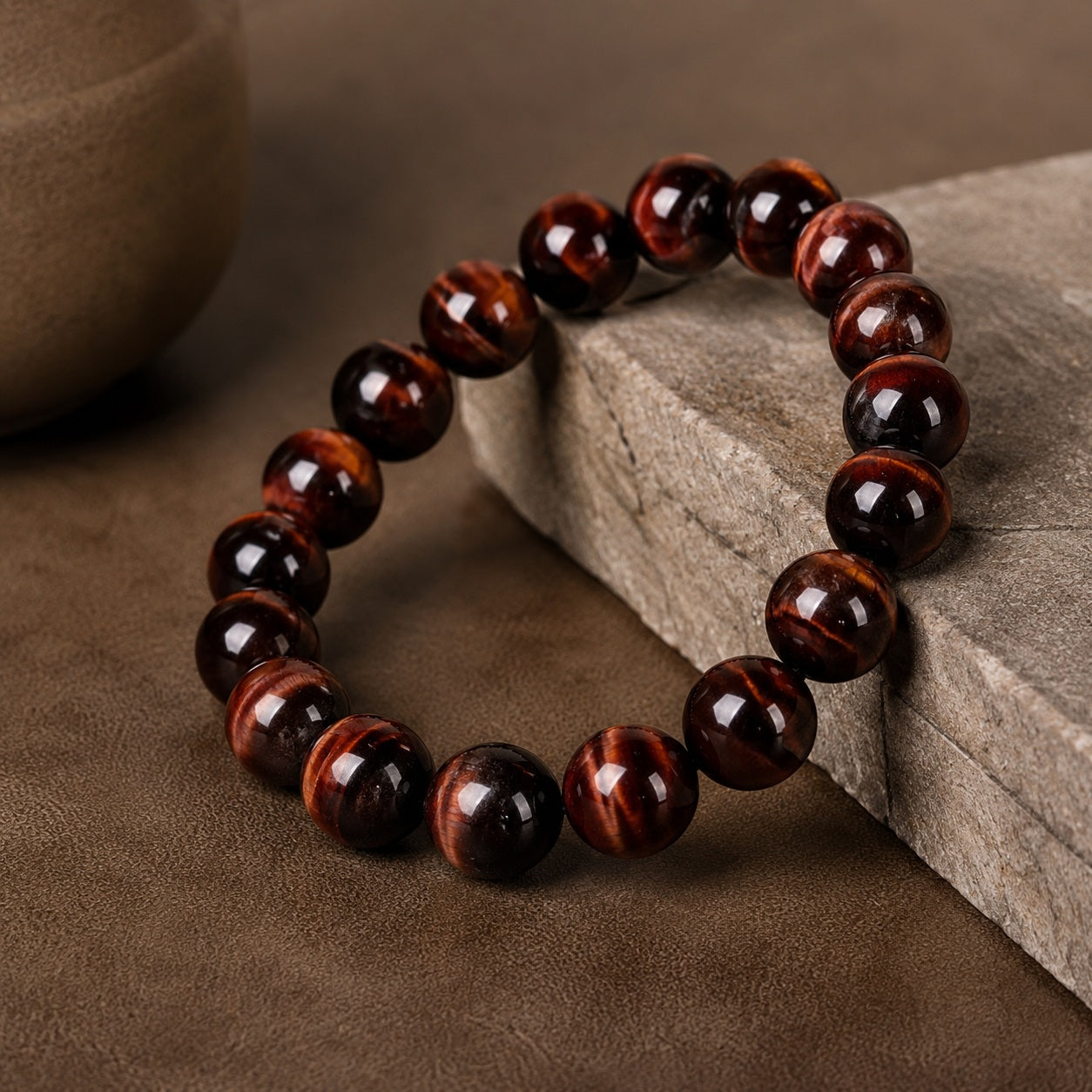 Red tiger’s eye bead bracelet styled on a textured brown surface