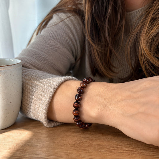 Close-up of a red tiger’s eye beaded bracelet worn on the wrist